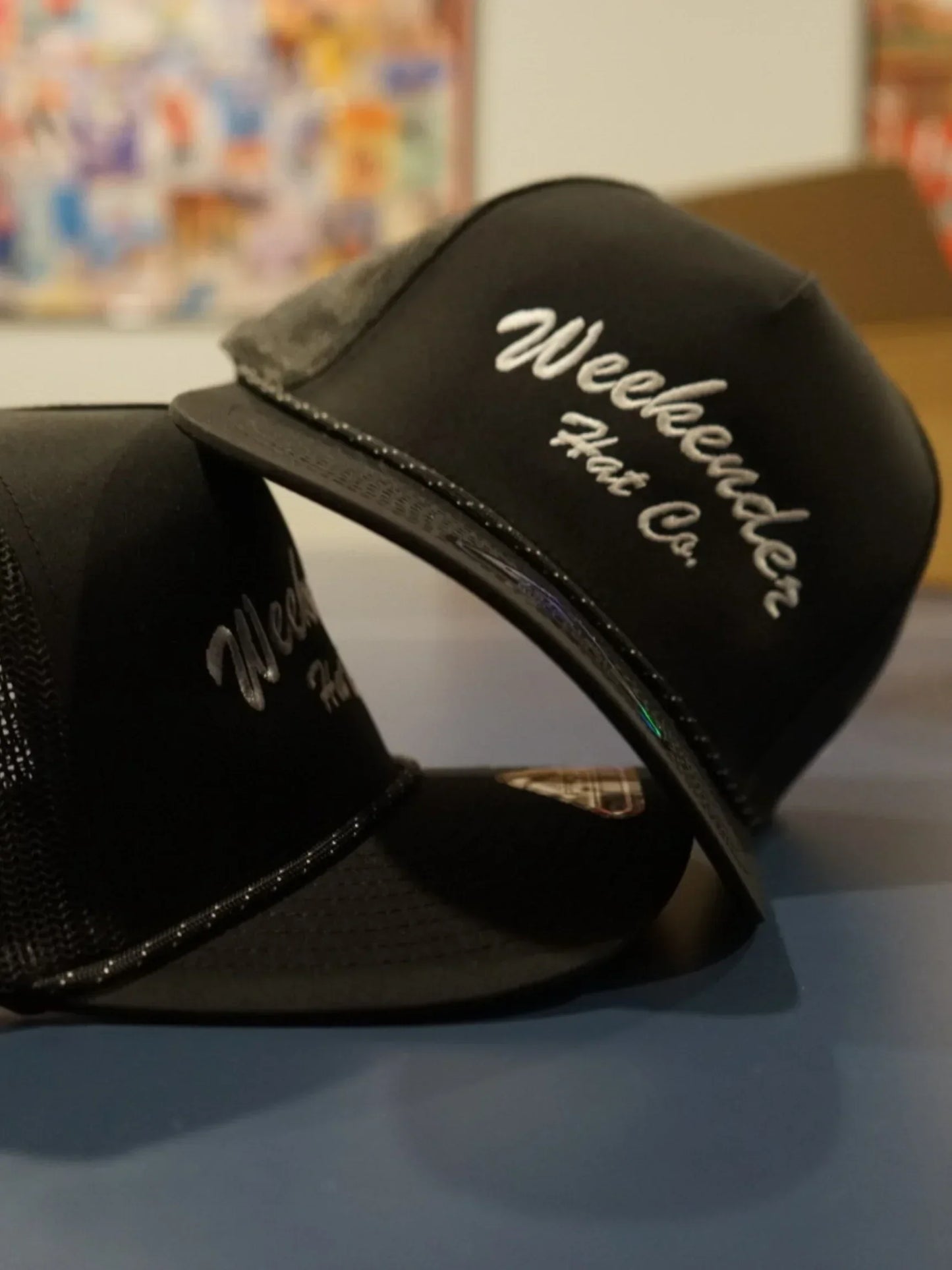 A photo of two black trucker hats from Weekender Hat Co.