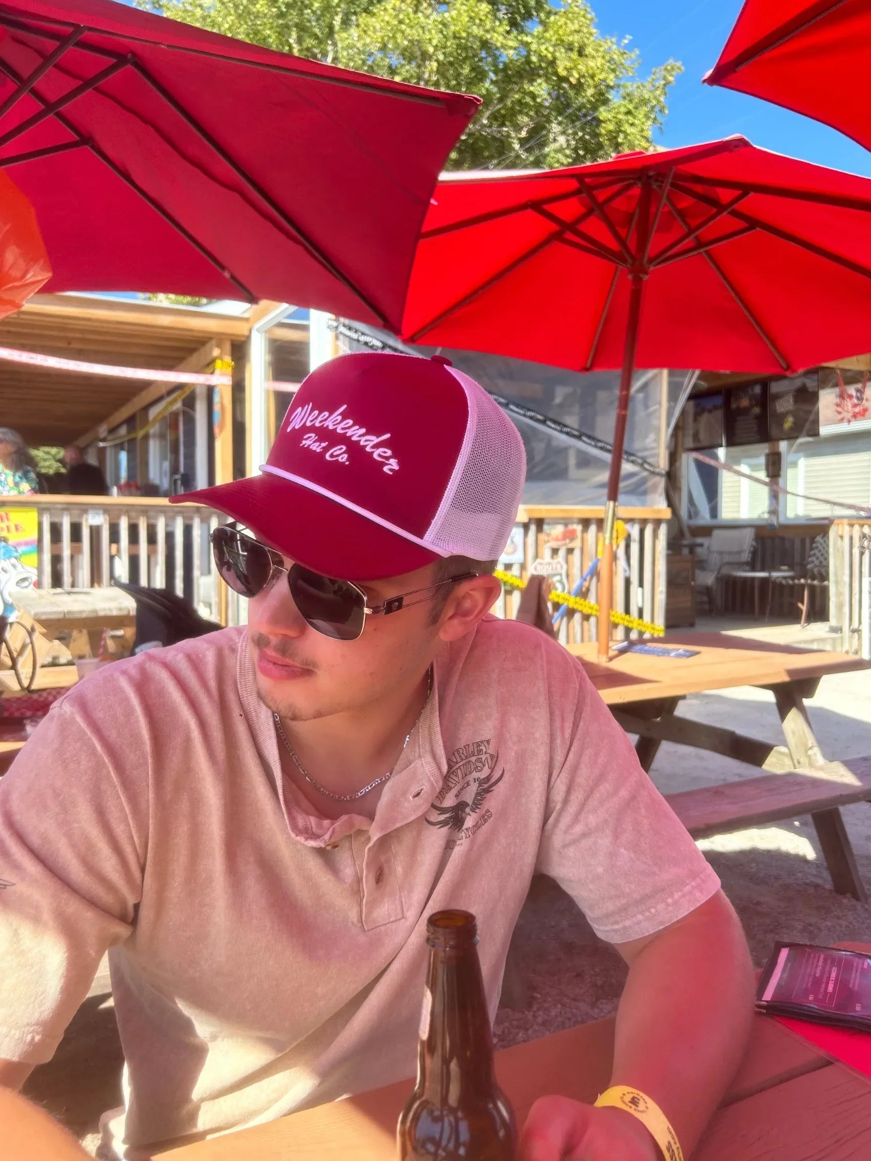 A photo of The Classic Weekender - Red Trucker Hat being worn at the beach bar