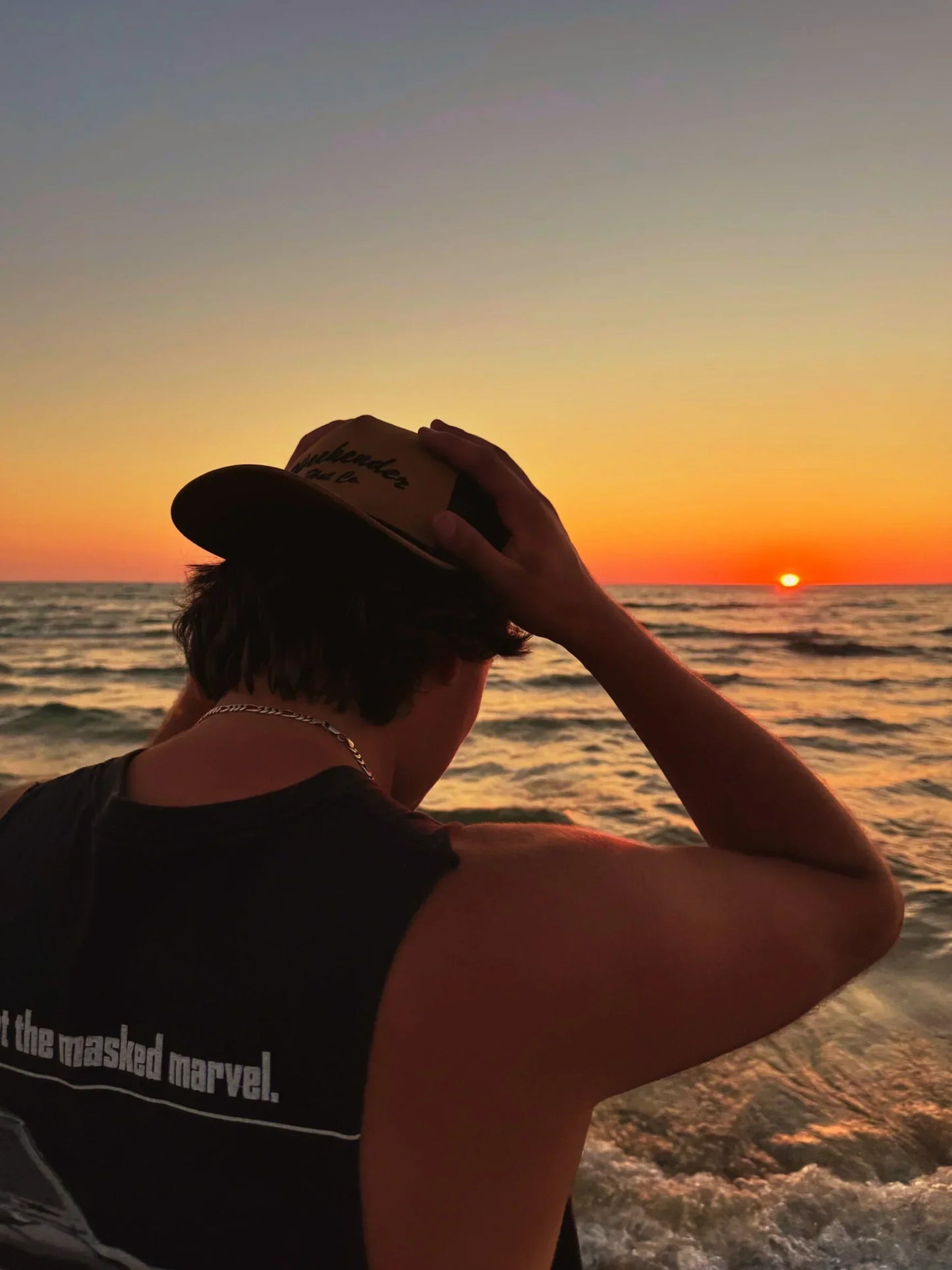 A photo of The Classic Weekender - Tan Trucker Hat being worn watching the sunset at the beach